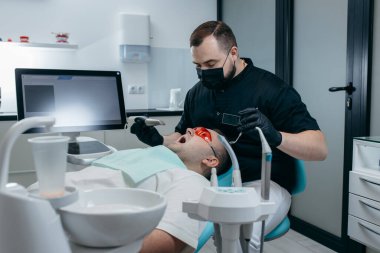 Dişçi, erkek hastanın dişlerini modern 3D tarama makinesiyle tarıyor.