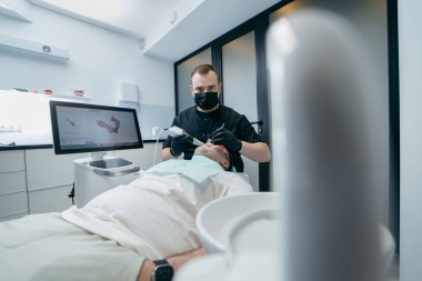 Dişçi, erkek hastanın dişlerini modern 3D tarama makinesiyle tarıyor.