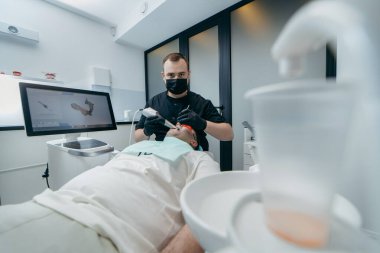 Dişçi, erkek hastanın dişlerini modern 3D tarama makinesiyle tarıyor.