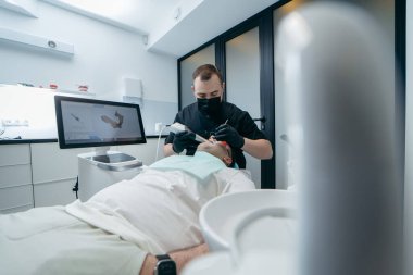 Dişçi, erkek hastanın dişlerini modern 3D tarama makinesiyle tarıyor.