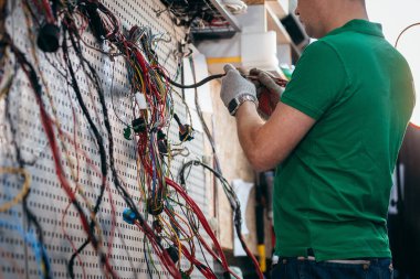 Genç mühendis traktörden elektrik kablolarını kontrol ediyor ve onarıyor