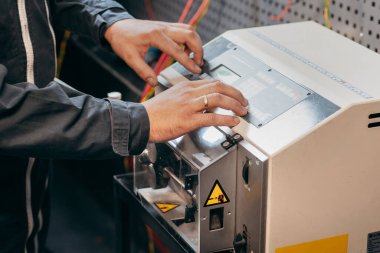 Elektrik teknisyeninin elleri kablo kesme makinesinde çalışıyor.