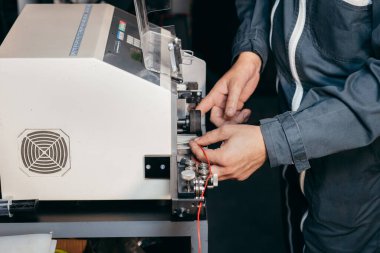 Elektrik teknisyeninin elleri kablo kesme makinesinde çalışıyor.