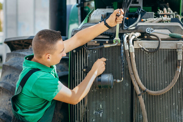 Молодой механический ремонт трактора на открытом воздухе