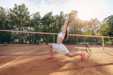 Genç bir kadın yazın dışarıda tenis oynuyor.