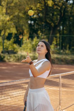 Genç bir kadın yazın dışarıda tenis oynuyor.