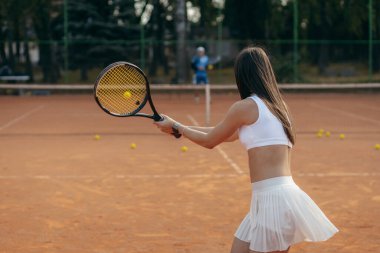Genç bir kadın yazın dışarıda tenis oynuyor.