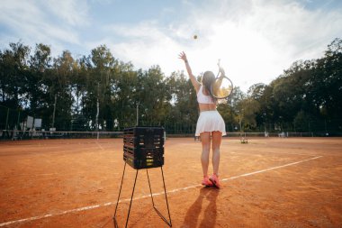 Genç bir kadın yazın dışarıda tenis oynuyor.