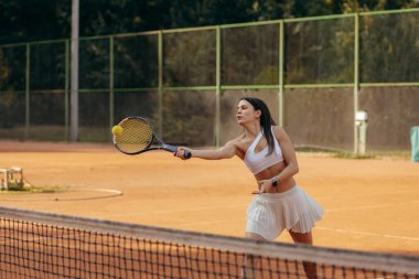 Genç bir kadın yazın dışarıda tenis oynuyor.