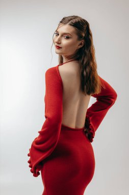 Stüdyoda beyaz arka planda kırmızı elbiseli genç kız.