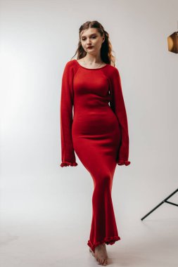 Stüdyoda beyaz arka planda kırmızı elbiseli genç kız.