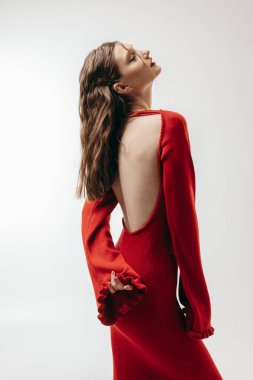 Stüdyoda beyaz arka planda kırmızı elbiseli genç kız.