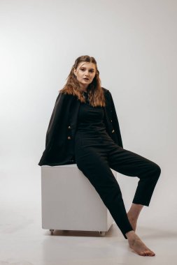 Stüdyoda beyaz arka planda siyah takım elbiseli başarılı bir iş kadını.