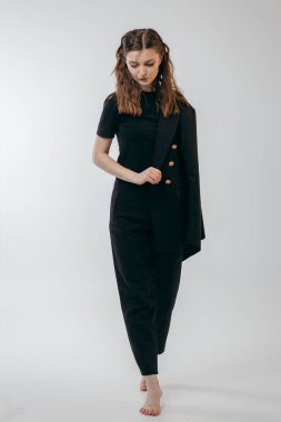 Stüdyoda beyaz arka planda siyah takım elbiseli başarılı bir iş kadını.