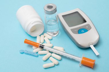 Glukometre ve insülin şırıngası, kesici alet test şeridi. Mavi arkaplanda.