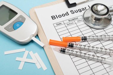 Glukometre ve insülin şırıngası, kesici alet test şeridi. Mavi arkaplanda.