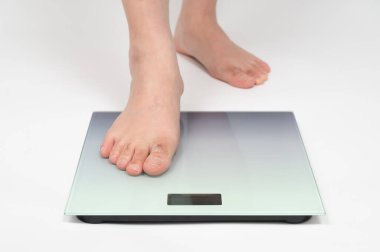 Orta yaşlı Asyalı bir adamın ayakları ağırlığını ölçüyor