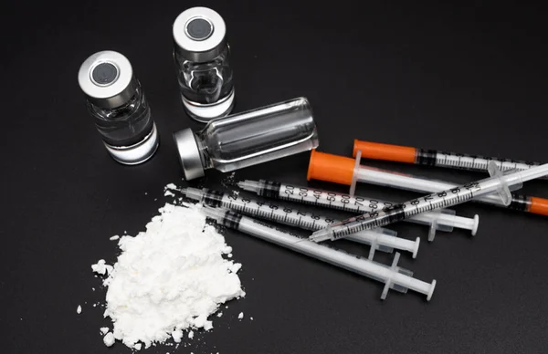 黒の背景に白い粉と使い捨て注射器と薬物犯罪の概念 — ストック写真