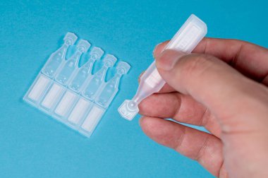 Tek kullanımlık göz damlaları mavi arkaplanda izole edildi