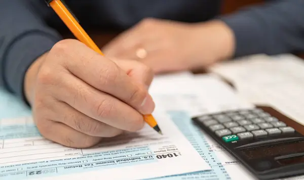 A man organizing individual income tax return form 1040 and receipts. Blurred background. Tax time.Tax concept. Close-up.