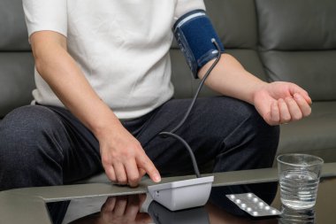 Tansiyon monitörü kullanan orta yaşlı bir adam.