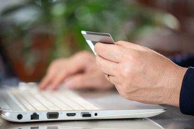 Asyalı orta yaşlı bir adamın elleri kredi kartı bilgilerini giriyor