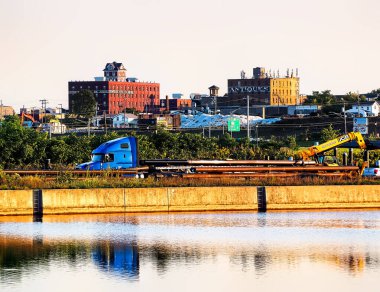 Syracuse, New York, USA. September 4, 2024. View of Syracuse's northside industries from the Inner Harbor. Crane and construction equipment in foreground for an aquarium and revitalization projects clipart