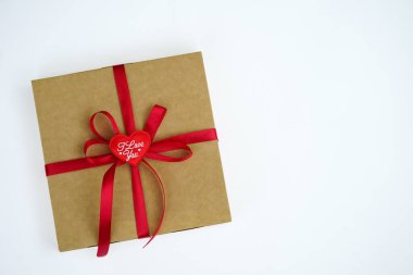 A gift wrapped in a kraft box with a red satin ribbon was isolated on white. The concept of a gift, New Year, Valentine's Day, Birthday, greetings