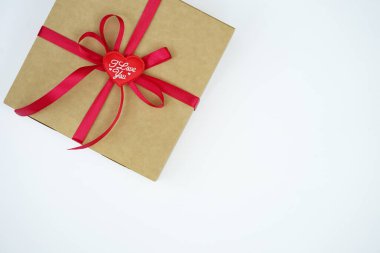 A gift wrapped in a kraft box with a red satin ribbon was isolated on white. The concept of a gift, New Year, Valentine's Day, Birthday, greetings