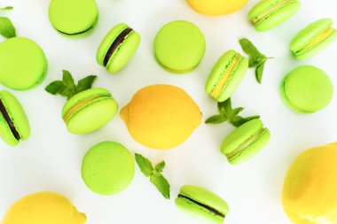 Green macaron with chocolate filling. Top view, layout with lemon and mint, confectioner