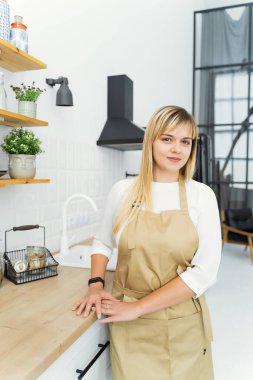 The pastry chef girl is standing in the kitchen in a beige apron