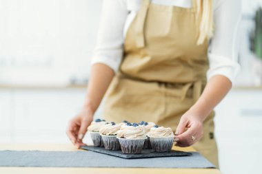 Women's hands of a confectioner, trim cupcakes with berries
