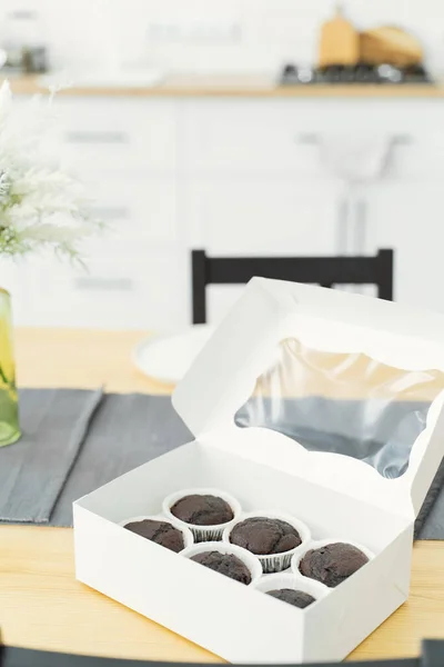 Cupcakes without decoration in a paper box for delivery. Sweet food delivery. Chocolate muffins, menu design or recipe background