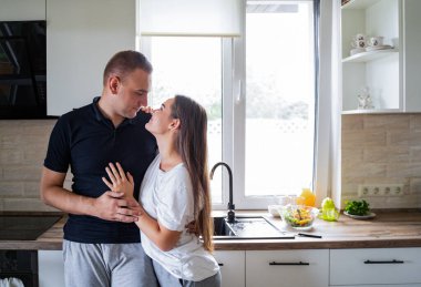 Modern bir mutfakta sevgi dolu evli bir çift ayakta ve sarılıyorlar. İlişki konsepti, aşk, ev, kahvaltı. Yüksek kalite fotoğraf