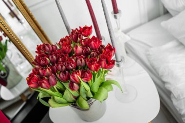 Komodinin üzerinde bir buket kırmızı lale. Anneler Günü, Sevgililer Günü