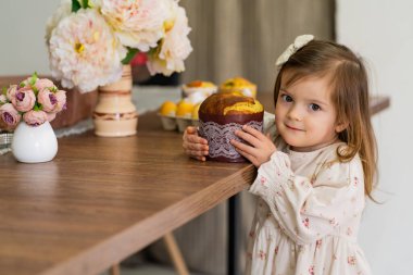 Kız masanın yanında duruyor ve elinde paskalya pastası tutuyor. Paskalya, aile, kutlama. Yüksek kalite fotoğraf