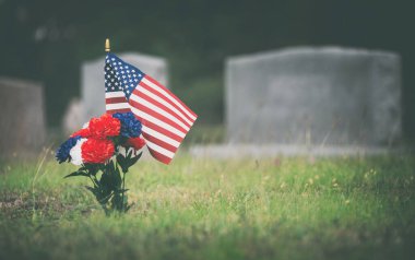 Gazinin mezarında Amerikan bayrağı ve kırmızı, beyaz ve mavi çiçekler. Anma Günü 'nde mezarlıkta ölen bir askeri onurlandırmak..