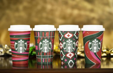 Dallas, Teksas - 4 Kasım 2023: 2023 tarihli yeni tasarlanmış tatil kupalarında bir dizi Starbucks içeceği. Altın arkaplana karşı ahşap masada görüntülendi.