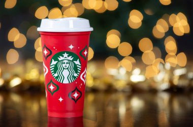 Dallas, Teksas - 17 Kasım 2023: 2023 tarihli Starbucks kahvesi tasarlanmış kırmızı kupa, yeniden kullanılabilir bir tatil kupası. Noel arkaplanına karşı gösterilen.