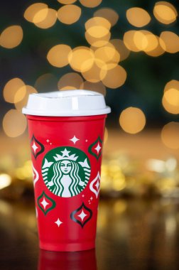 Dallas, Teksas - 17 Kasım 2023: 2023 tarihli Starbucks kahvesi tasarlanmış kırmızı kupa, yeniden kullanılabilir bir tatil kupası. Noel arkaplanına karşı gösterilen.