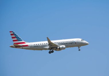 IRVING, ABD - 26 Mayıs 2024: Amerikan Kartal uçağı Embraer ERJ-175 Dallas Fort Worth Uluslararası Havaalanına (DFW) yaklaşıyor, mavi gökyüzü.