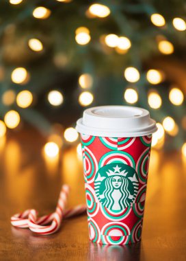 Dallas, Teksas - 12 Kasım 2024: 2024 tarihli yeni tasarlanmış tatil kupasında Starbucks kahvesi. Tahta masanın üzerinde şeker kamışlarıyla sergileniyordu. Tatil bokeh arkaplanı.