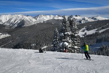Skiing and snowboarding on the beautiful sunny day at the Vail Mountain Ski Resort. Amazing top view to the peaks of the Colorado Rockies.