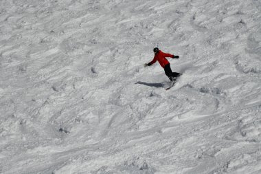 Snowboarder downhill in fresh snow leaving snow powder behind. Action photo.