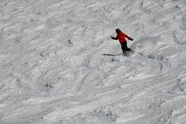 Snowboarder running down the slope leaving behind a snow powder.
