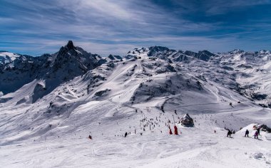 Fransa 'daki Courchevel kayak merkezindeki dağların nefes kesici manzarası. Aktif kış tatili, kayakçılar ve snowboardcular yamaçlardan aşağı iniyor.. 