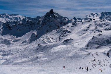 Fransa 'daki Courchevel kayak merkezindeki dağların nefes kesici manzarası. Aktif kış tatili, kayakçılar ve snowboardcular yamaçlardan aşağı iniyor.. 