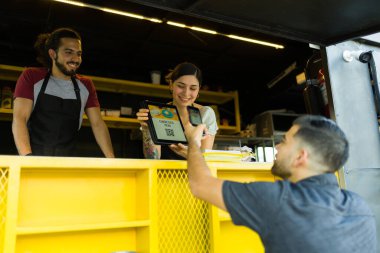 Latin adam akıllı telefonunda QR kodu kullanarak fast food kamyonunun menüsüne bakıyor. 