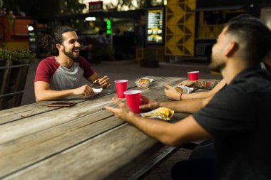 İspanyol arkadaşlar sokak yemeklerinden taco yerken gülüp eğleniyorlar.