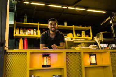 Neşeli çekici aşçı müşteriyi beklerken gülümsüyor gece boyunca fast food kamyonunda.